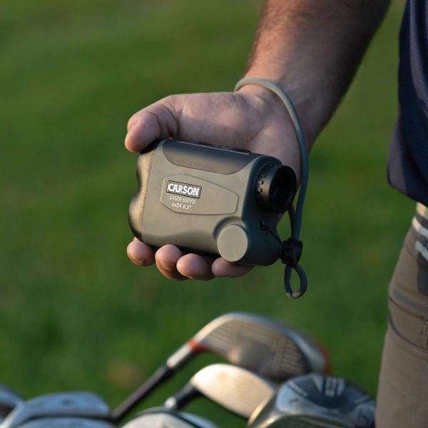 Golfer holding Carson LiteWave Pro RF-700 Laser Rangefinder golf accessory using convenient wrist strap for high performance