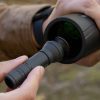 Jäger mit Jumbo leichtgewichtigem, portablen, wiederverwendbaren Objektivreiniger, um das Objektiv eines Carson Monokulars beim Wandern in der Natur zu reinigen