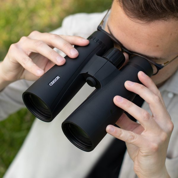 Campista usando binoculares Carson resistentes al agua con gafas para vista HD de imágenes con gran aumento, binoculares de 12x50 para observadores de aves